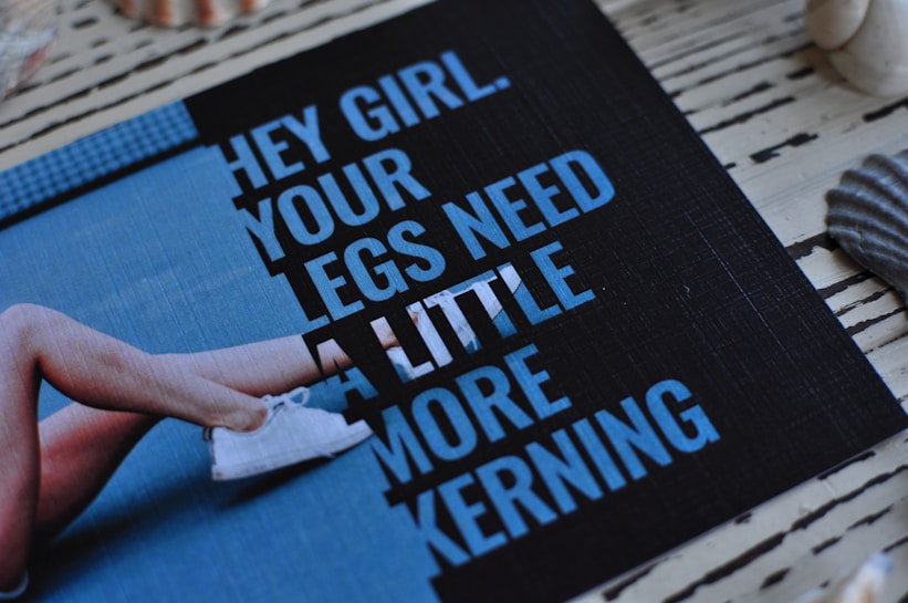 A printed card with a humorous text passage is placed on a striped wooden surface, surrounded by seashells and featuring an image of crossed legs in sneakers. The text humorously comments on typography spacing.