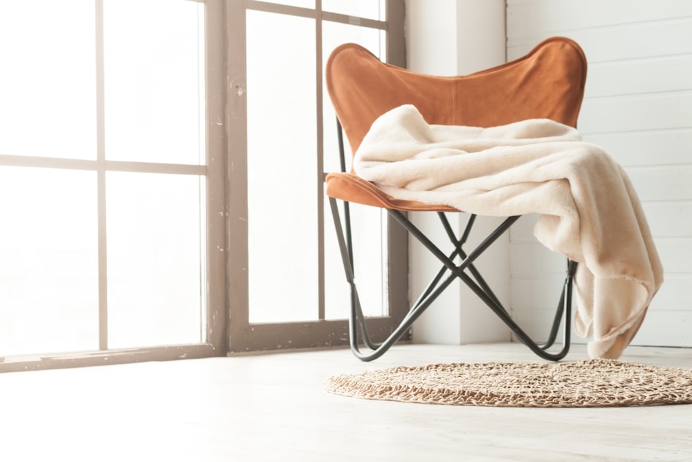 cadeira de madeira marrom perto do têxtil branco no piso de madeira marrom
