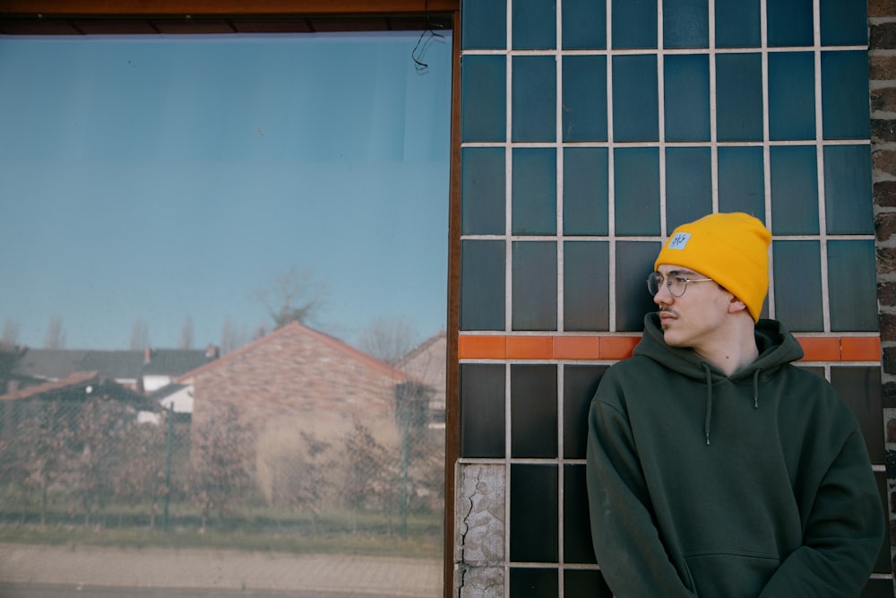 man in green hoodie standing near window