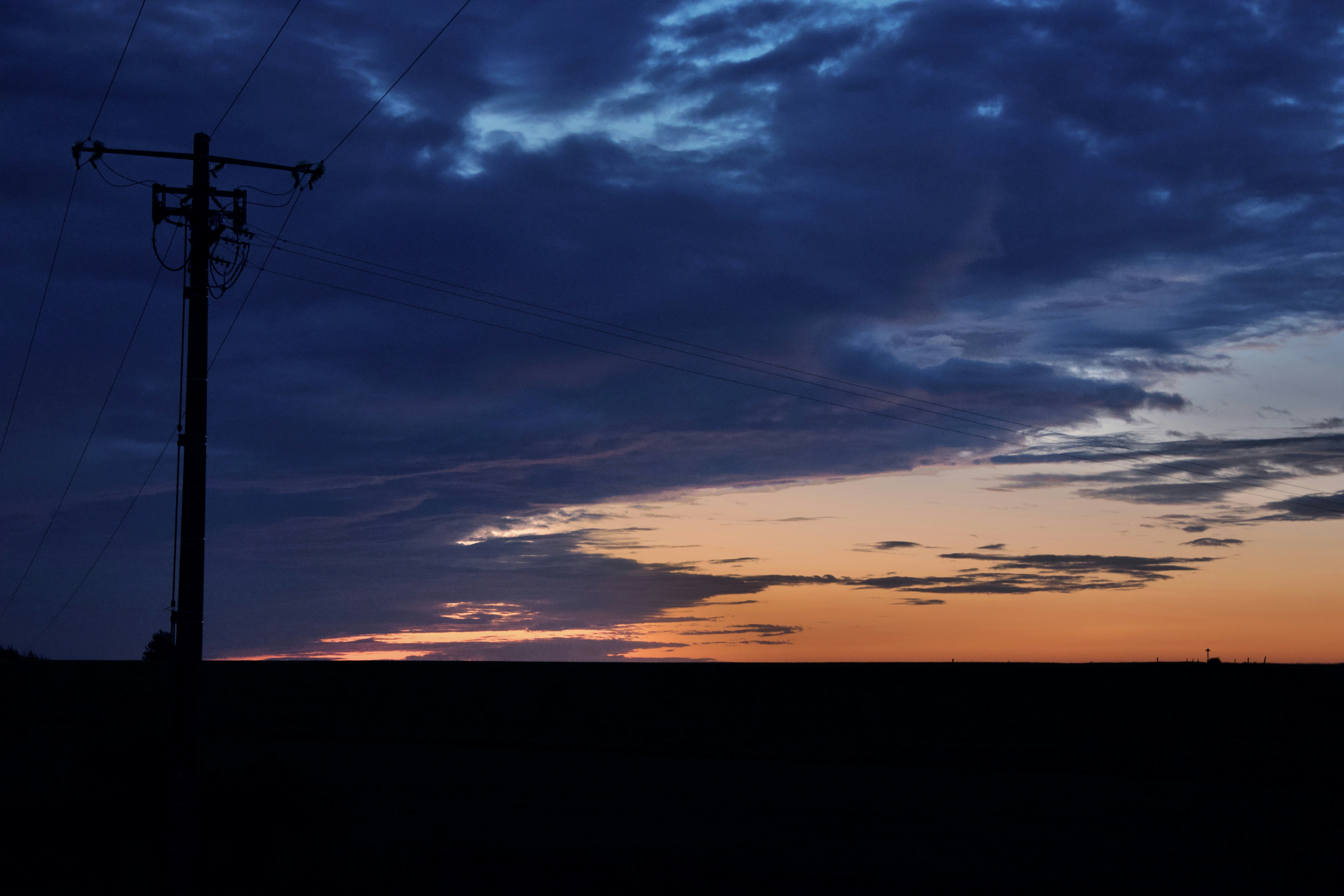 silhouette of electric post during sunset