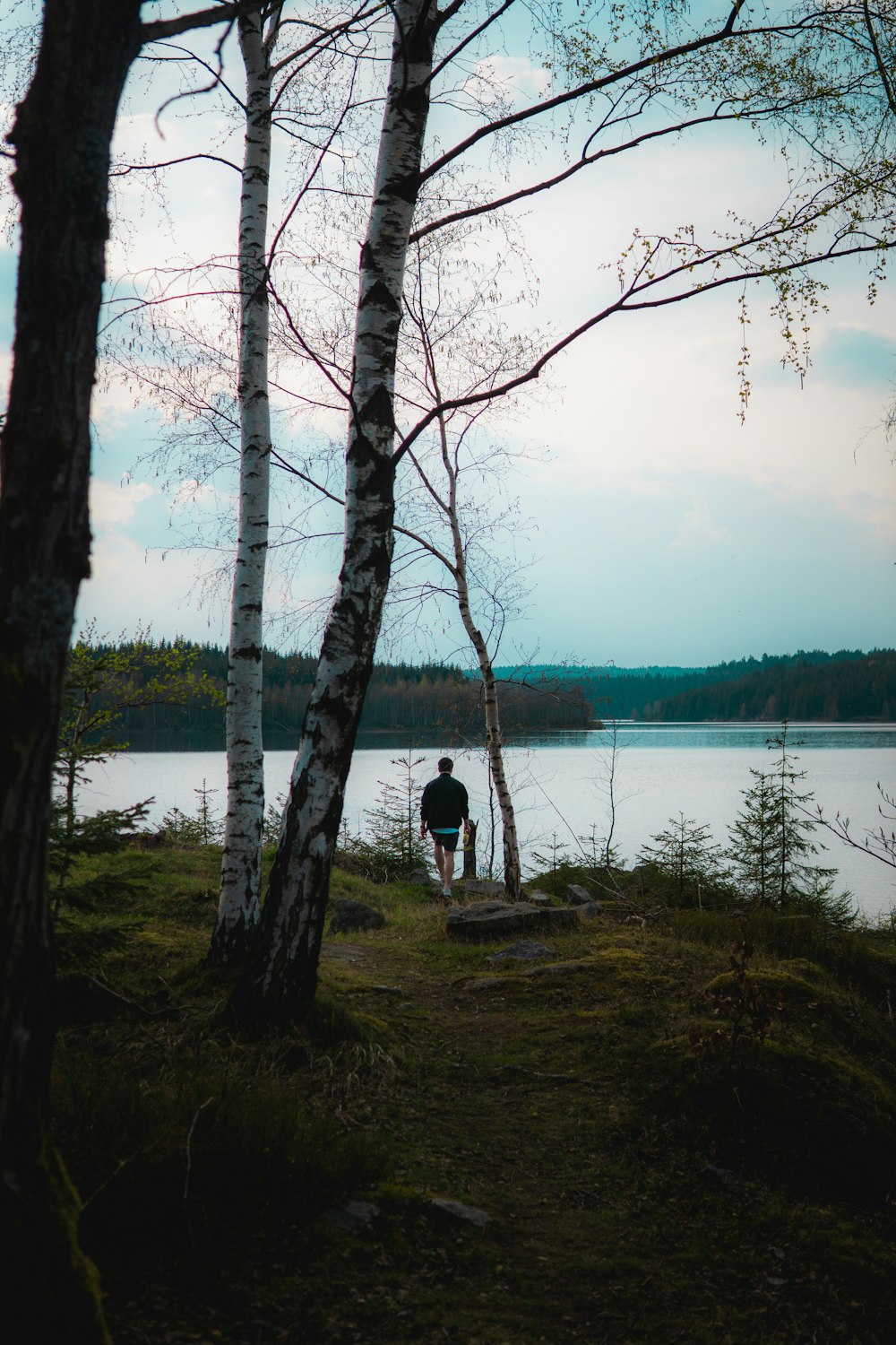 person in black jacket standing near lake during daytime