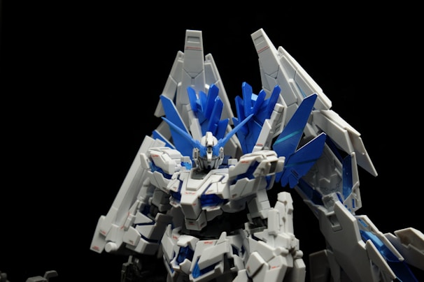 A highly detailed and intricate model of a robot or mecha with futuristic and angular design features. The model has a prominent color scheme of white and blue, with various sharp and pointed elements resembling wings or armor plating. The structure appears mechanical and advanced, set against a plain black background that highlights its details.
