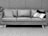 A three-seat leather couch with a mid-century modern design, adorned with patterned throw pillows. The couch is placed on a textured rug against a backdrop of a tiled wall. The overall setting appears minimalist and stylish.