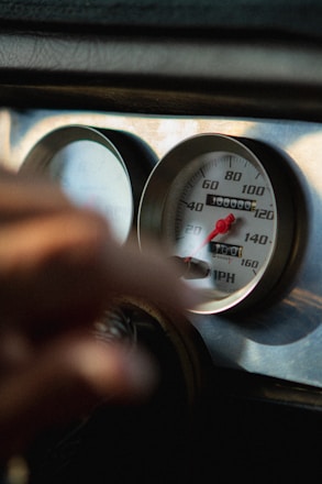 Close-up of a car speedometer showing a high speed on a busy road.