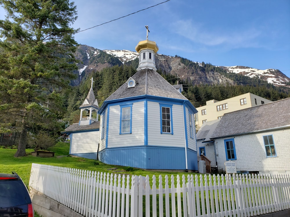 Maison en bois bleu et blanc près du champ d’herbe verte et de la montagne sous le ciel bleu pendant la journée