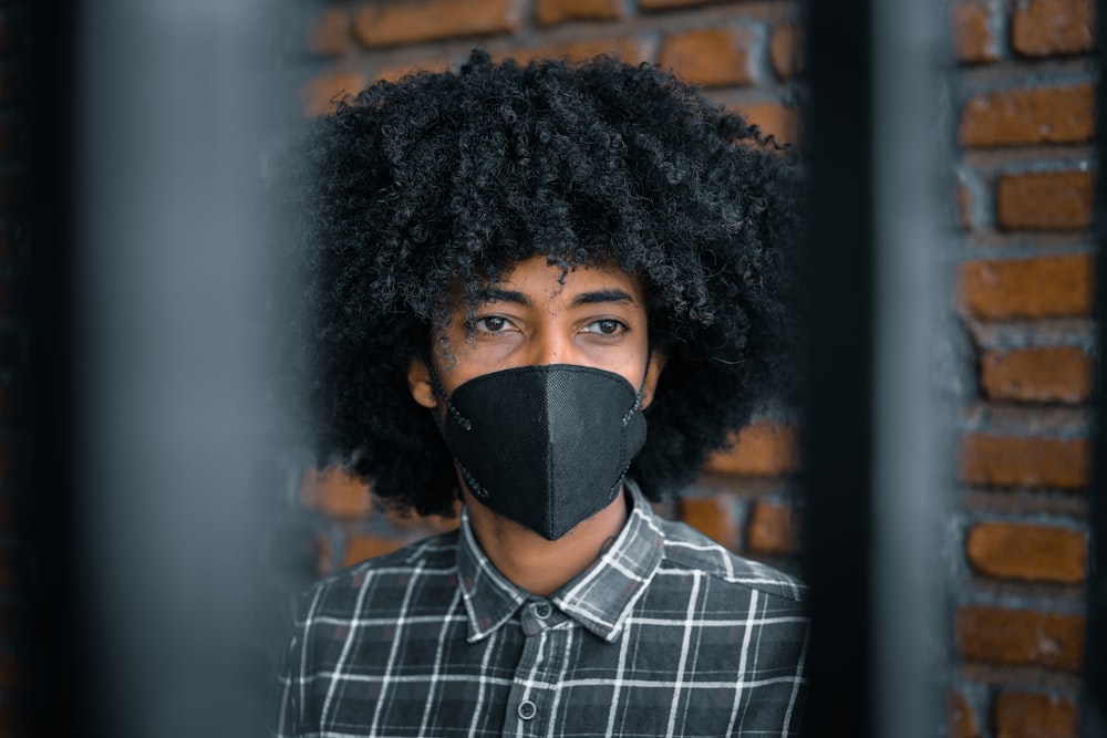 man in blue and white plaid dress shirt wearing black face mask