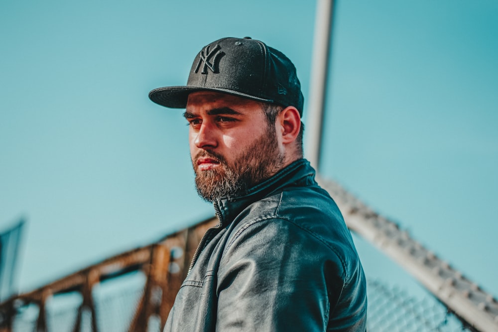 man in black leather jacket wearing black cap