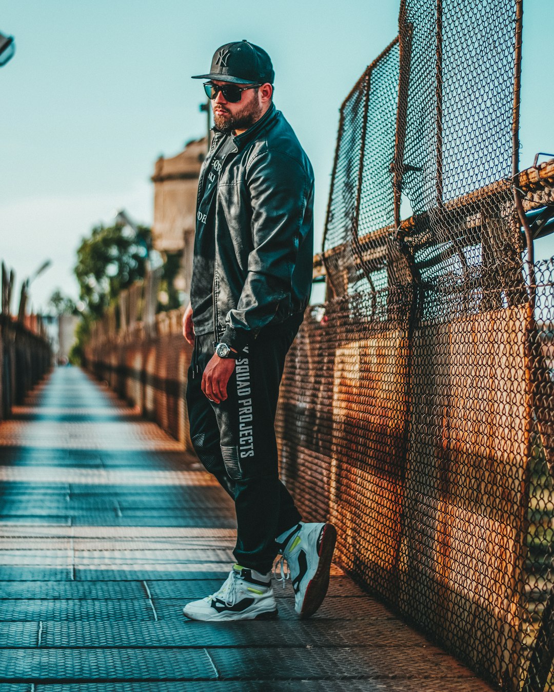 man in black leather jacket and black pants standing on sidewalk during daytime