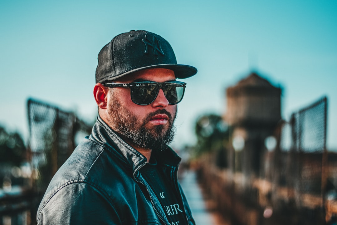 man in black leather jacket wearing black sunglasses and black cap