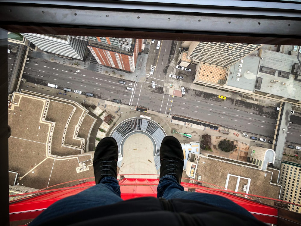 person in blue denim jeans and black sneakers sitting on red car