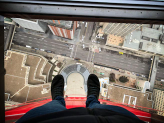 person in blue denim jeans and black sneakers sitting on red car