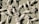 Decorative white metal or wrought iron artwork features intricate floral and leaf designs. The textured green wooden background contrasts with the light color of the metal, highlighting the delicate flower petals and swirling leaf patterns.