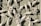Decorative white metal or wrought iron artwork features intricate floral and leaf designs. The textured green wooden background contrasts with the light color of the metal, highlighting the delicate flower petals and swirling leaf patterns.