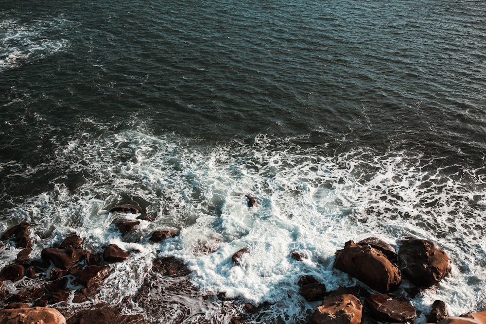 brown rocky shore with water waves during daytime