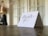 A thank you card with elegant cursive handwriting is propped up on a wooden table surface. The background is softly blurred, with a hint of warm lighting and some indistinct shapes.