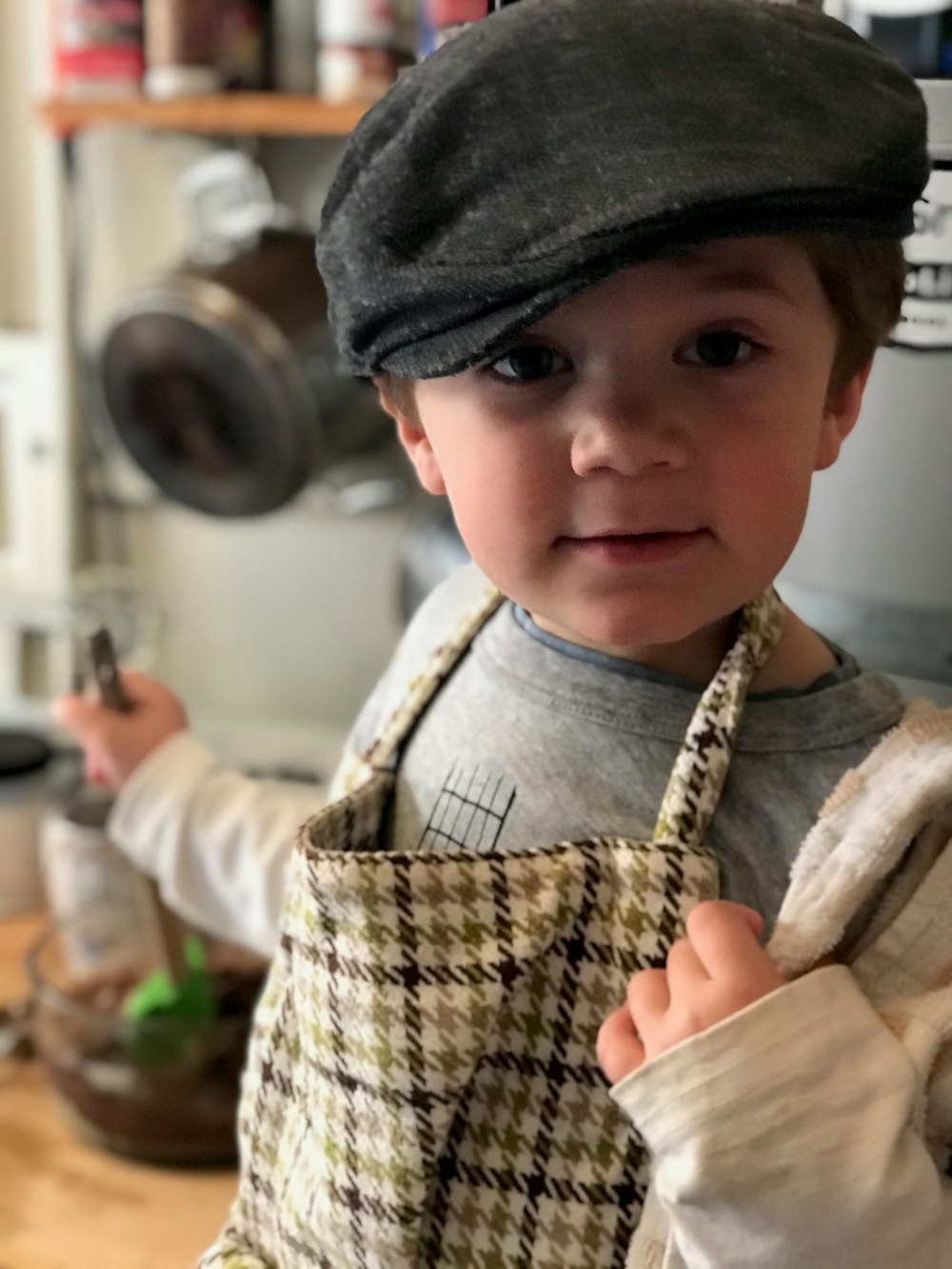 boy in black hat holding brown wooden chopping board