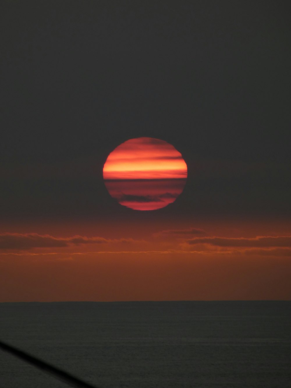 the sun is setting over the ocean with a boat in the foreground