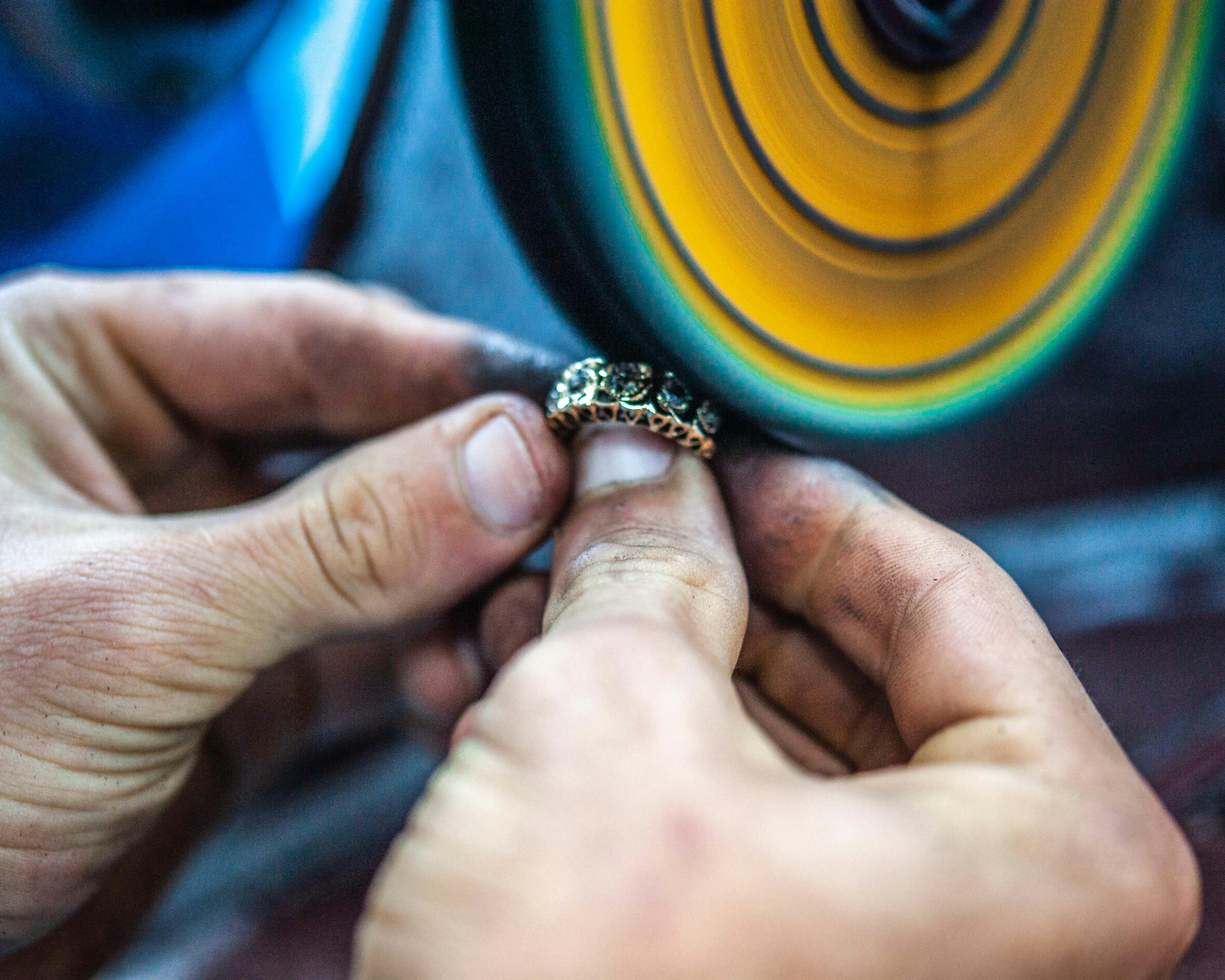 A jeweler examining a diamond ring with a loupe in a well-lit workshop