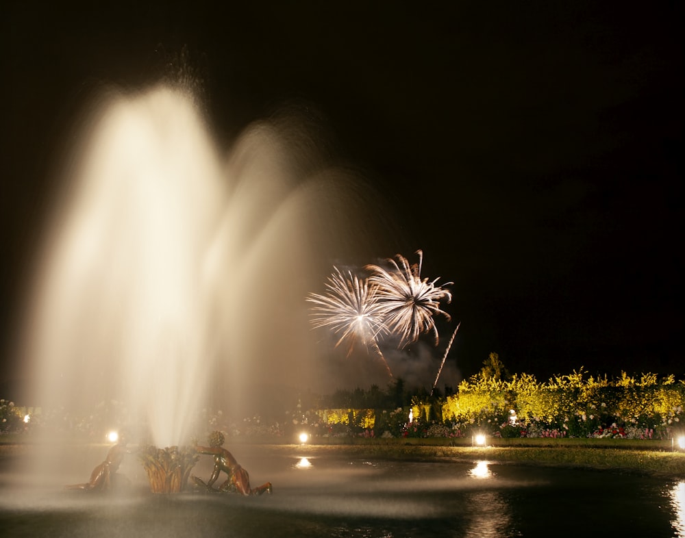 people sitting on bench near fountain during night time