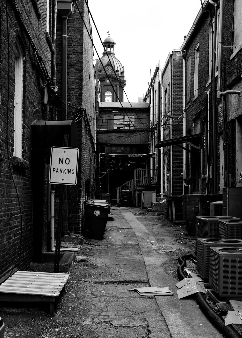 grayscale photo of man sitting on bench near building