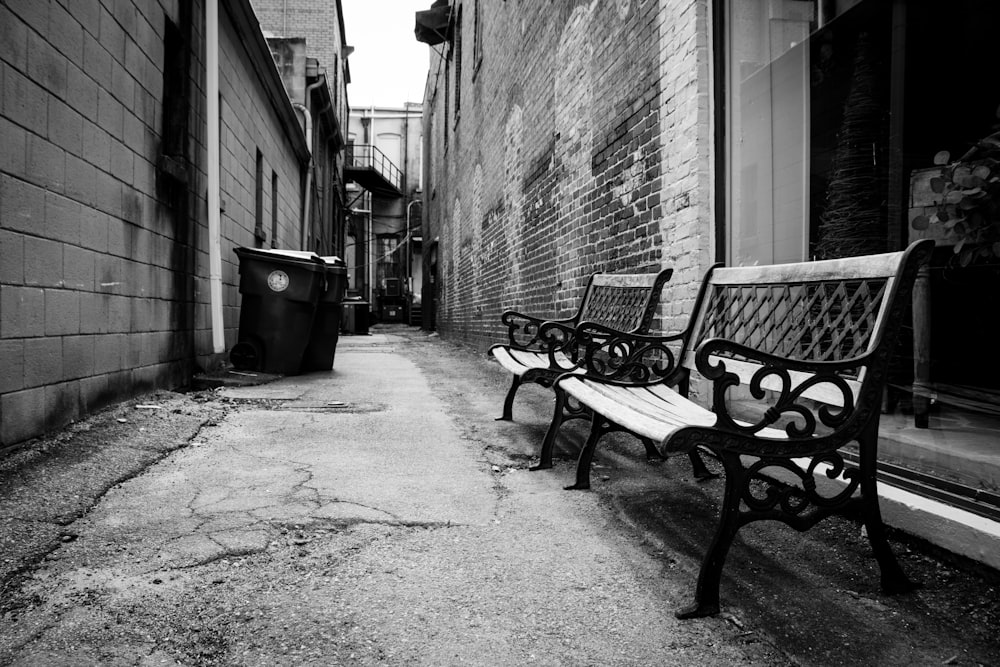 grayscale photo of empty bench beside building