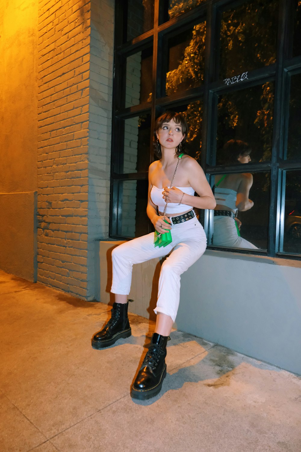 woman in white pants and black leather boots sitting on white chair