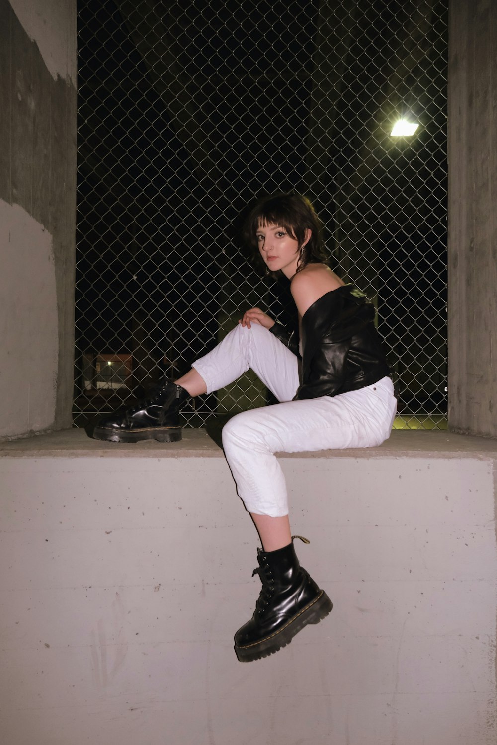woman in black long sleeve shirt and white pants sitting on white concrete bench