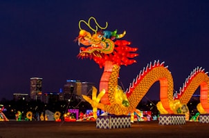people walking on street with dragon statue during night time