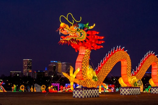 people walking on street with dragon statue during night time