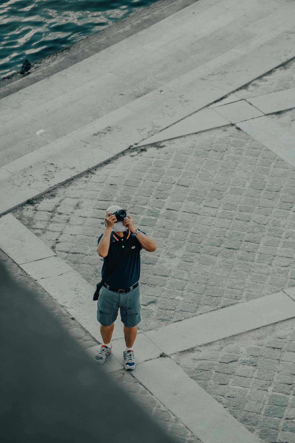 menino em shorts jeans azuis e camiseta cinza em pé no pavimento de concreto cinza