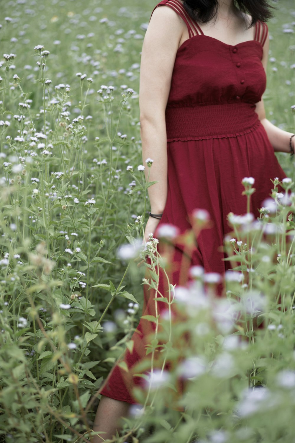 woman in red dress standing on green grass field during daytime