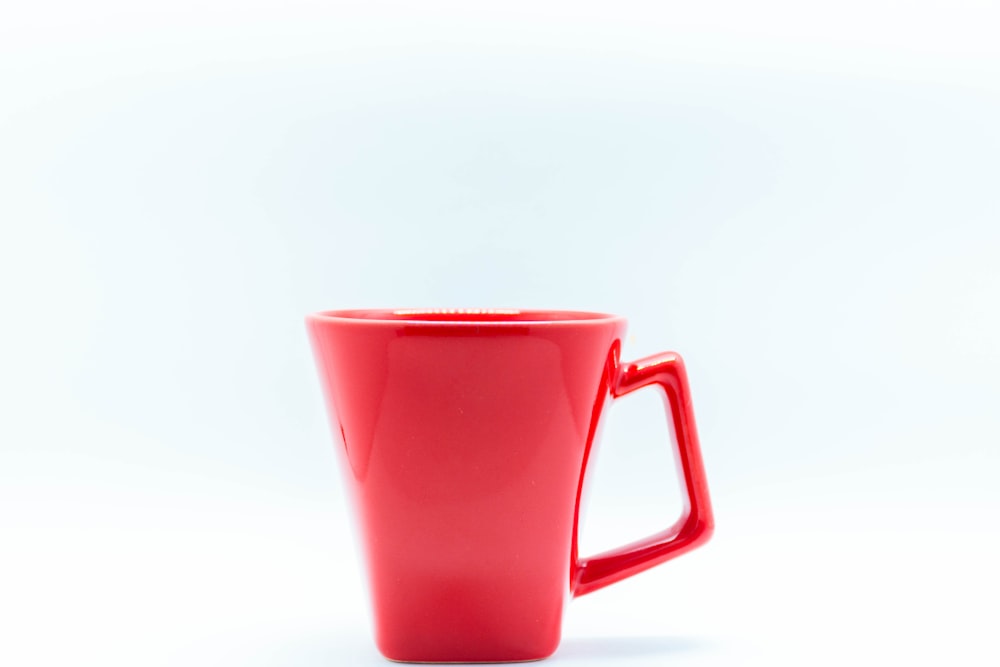 red ceramic mug on white table