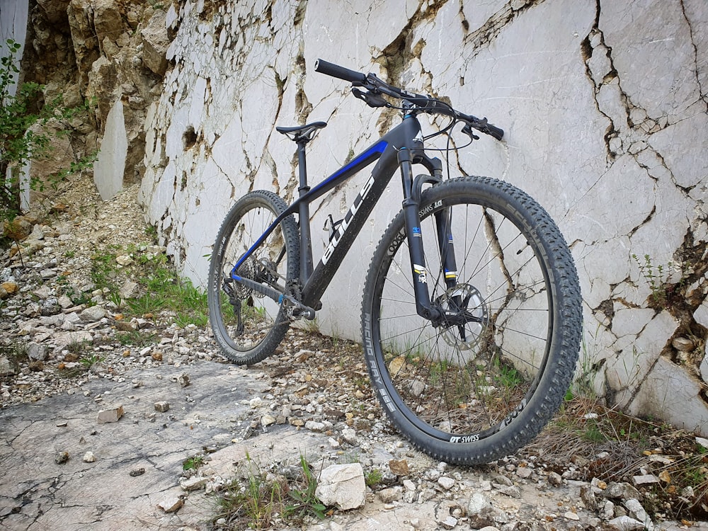 blue and black mountain bike leaning on white wall