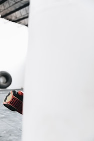 Boxing gloves in action, mid-punch against a punching bag with sweat droplets flying.