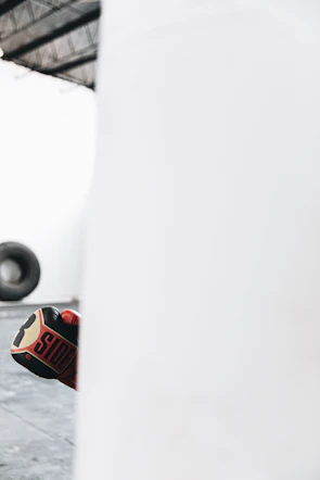Close-up of boxing gloves striking a heavy bag in a modern gym setting.
