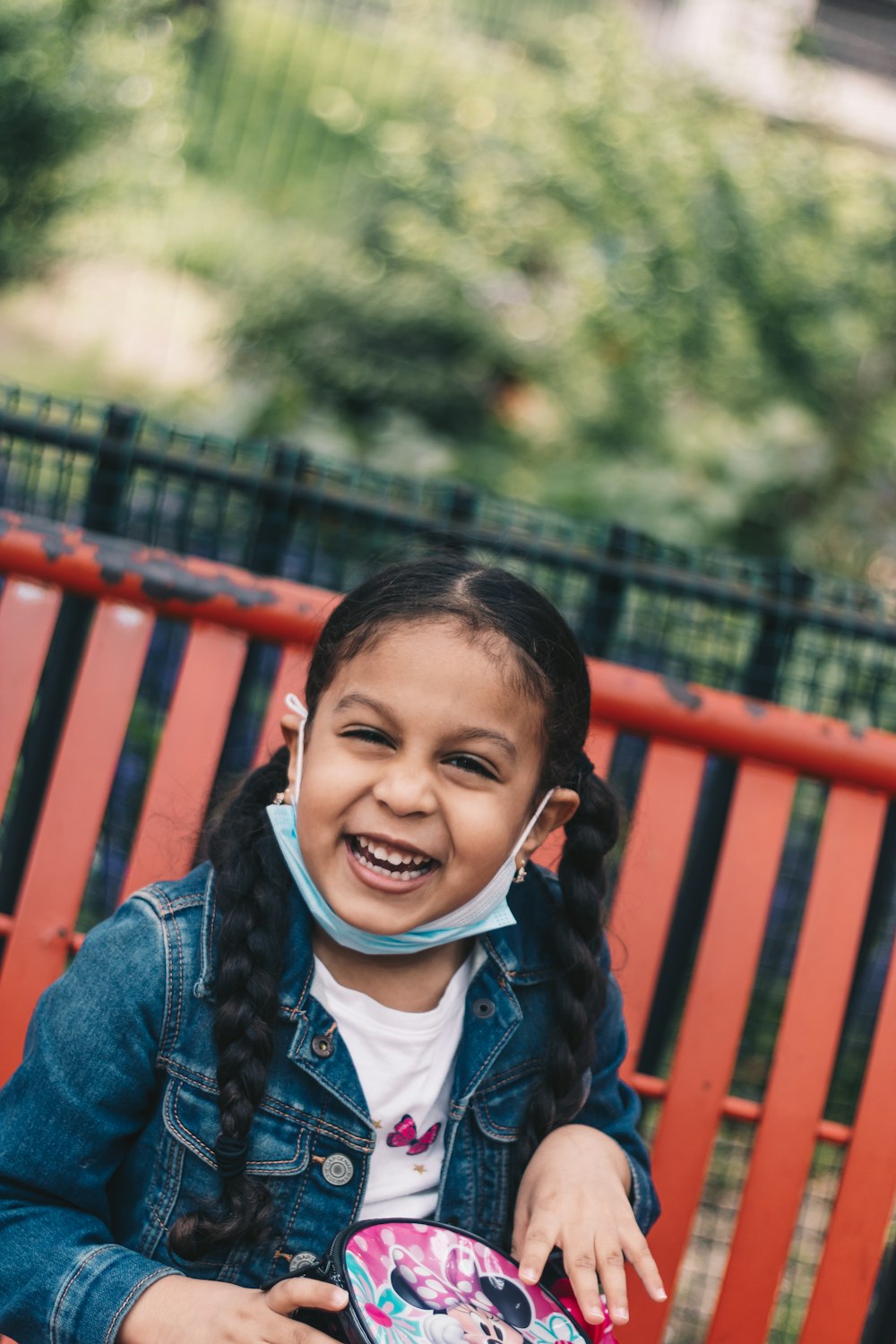 a little girl sitting on a red bench