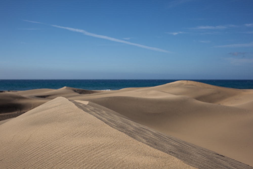 sabbia marrone sotto il cielo blu durante il giorno