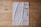 A document is laid out on a wooden surface. It appears to be a printed or photocopied sheet with tables and text written in Arabic. The paper is slightly crumpled and shows signs of wear. The wooden surface has a natural finish with visible knots and grain patterns.
