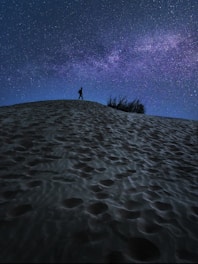 person standing on sand under blue sky during daytime
