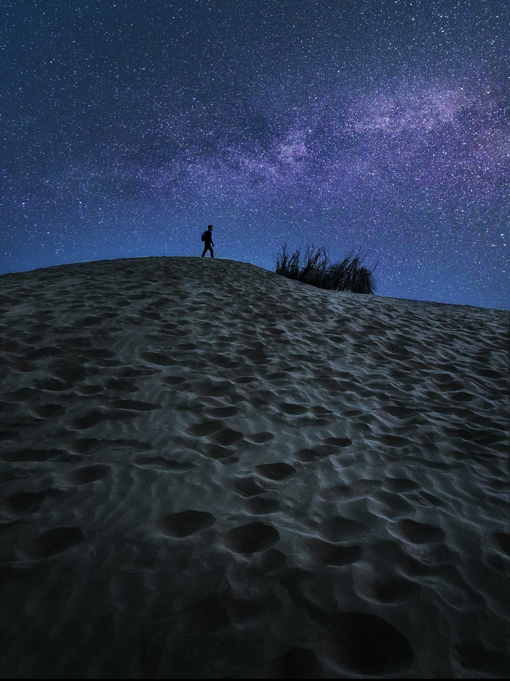 persona in piedi sulla sabbia sotto il cielo blu durante il giorno