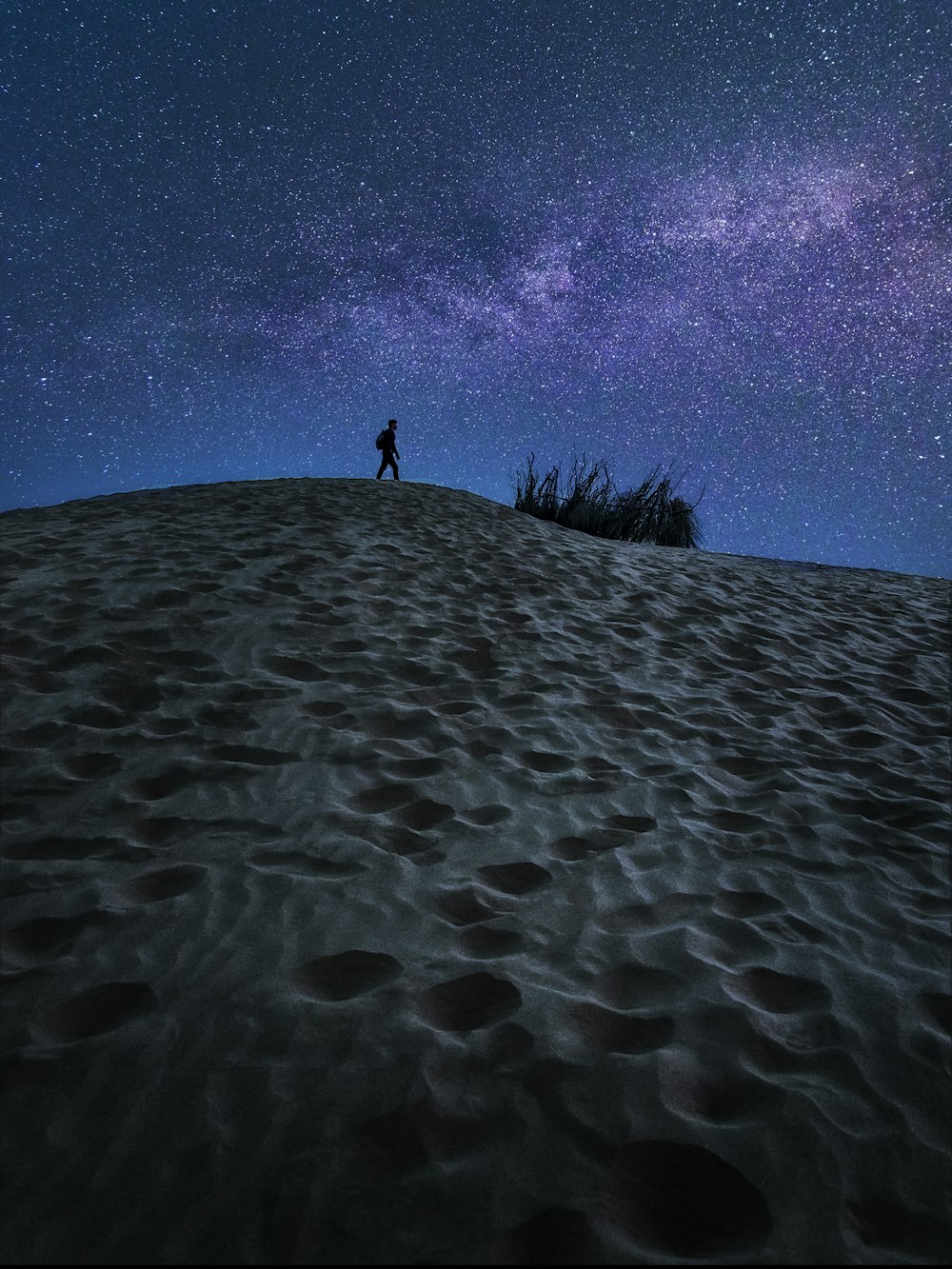 person standing on sand under blue sky during daytime