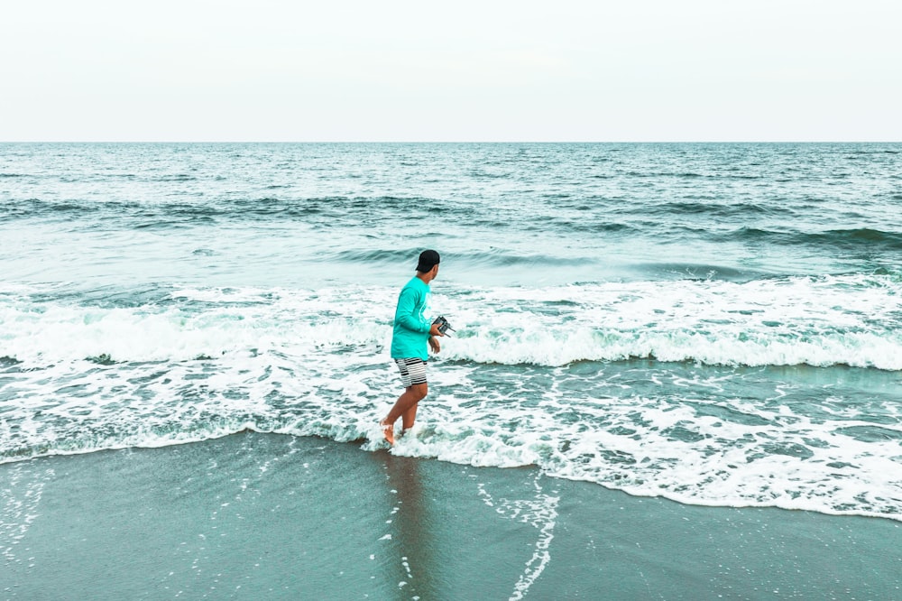 woman in blue shirt and white shorts walking on beach during daytime