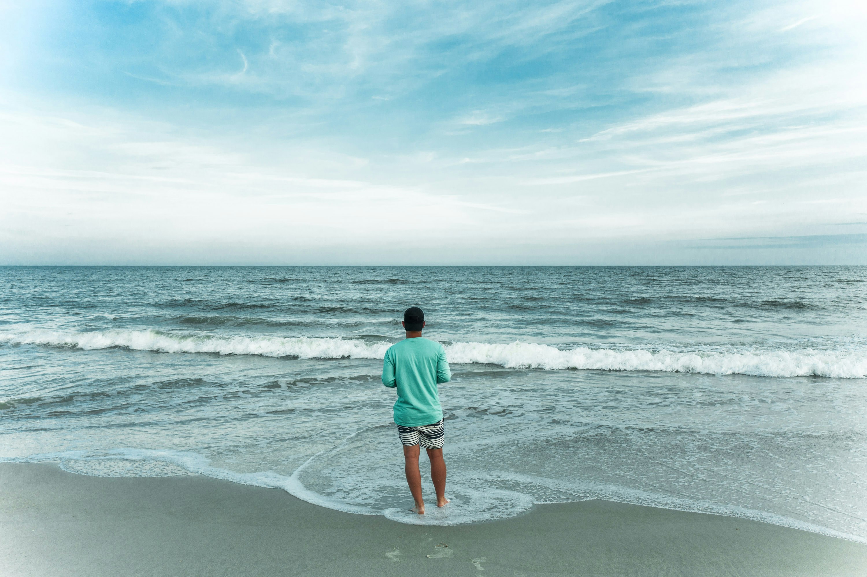 man in green shirt standing on beach during daytime