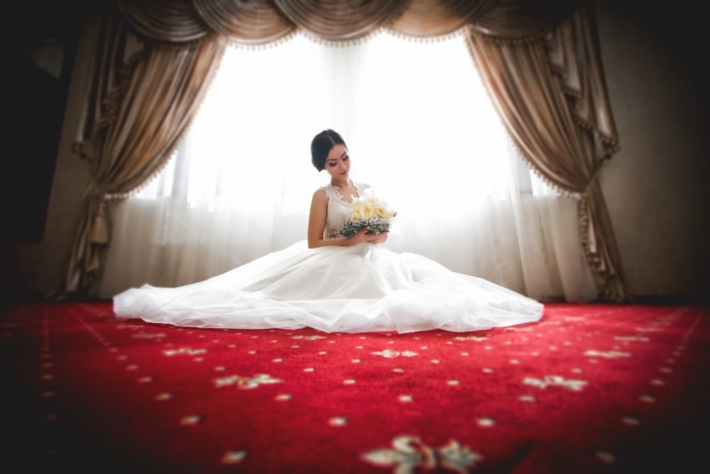 Frau im weißen Hochzeitskleid sitzt auf dem Bett