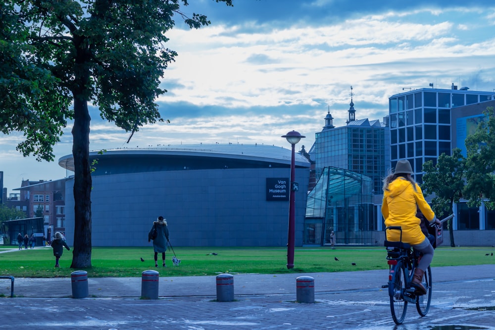 man in yellow jacket and black pants walking on sidewalk during daytime