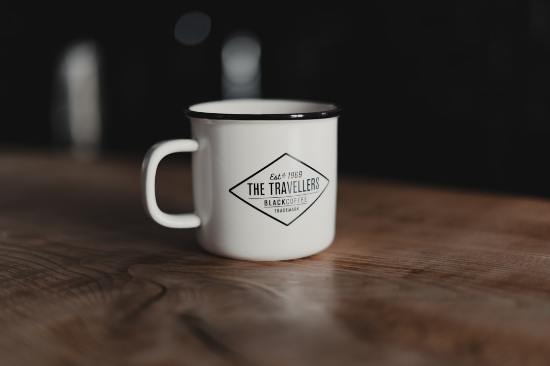 white and black ceramic mug on brown wooden table