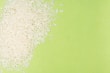 White rice grains are scattered over a bright green background, creating a contrast between the textures and colors.