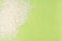 White rice grains are scattered over a bright green background, creating a contrast between the textures and colors.
