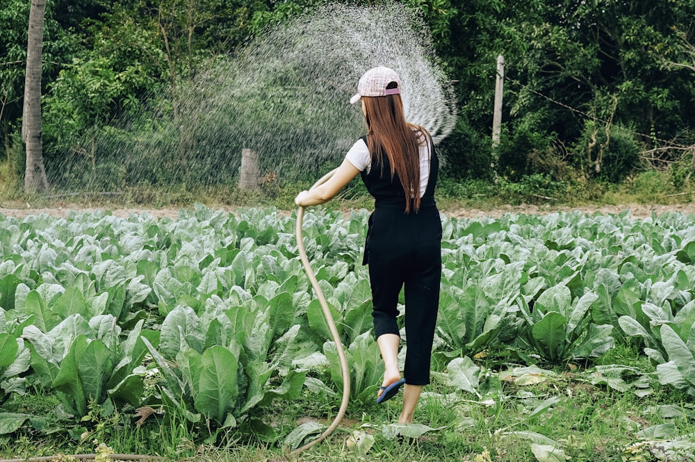 Femme en chemise à manches longues noire et pantalon noir debout sur un champ d’herbe verte pendant la journée