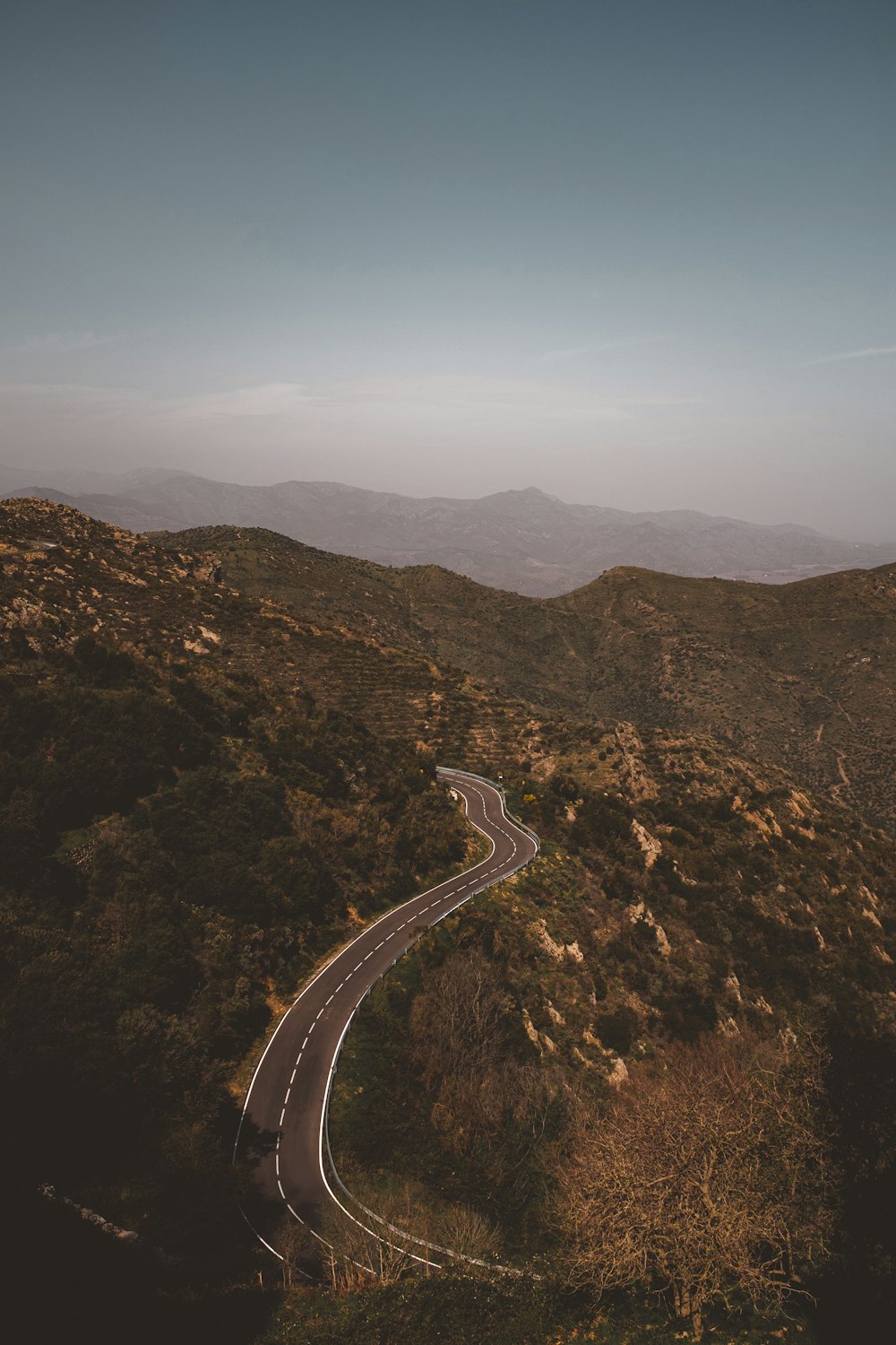 gray concrete road between brown mountains during daytime